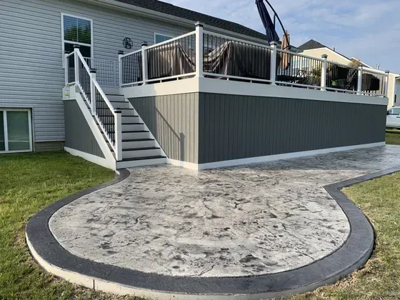 Stamped concrete patio in front of a raised deck